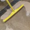 Yellow squeegee cleaning a wet floor.